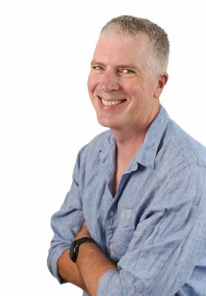 Photo of Driving Instructor Adam with arms crossed, smiling and wearing a blue collared shirt